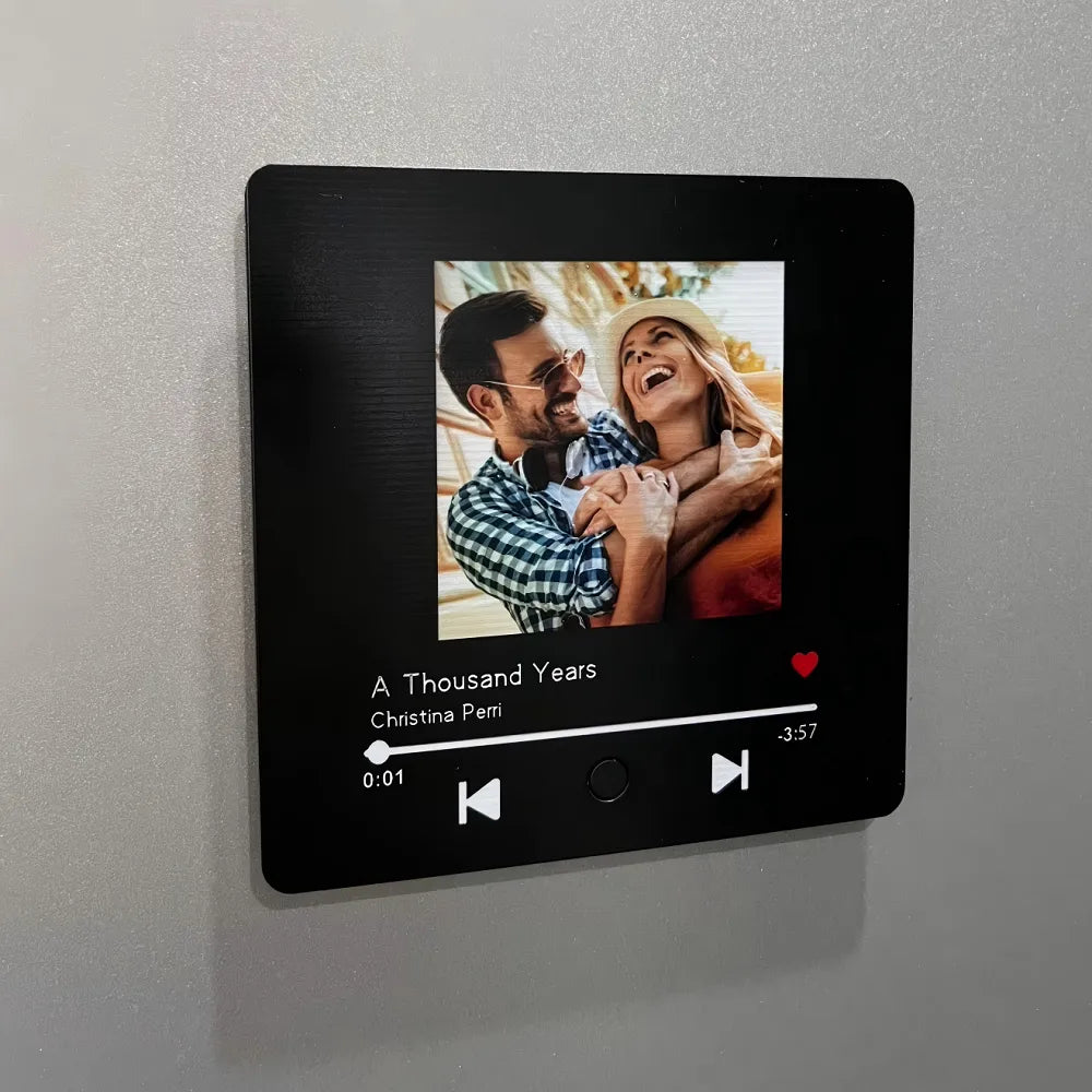 A happy couple using a custom music magnet on a kitchen fridge, illustrating a sentimental gift idea for loved ones.